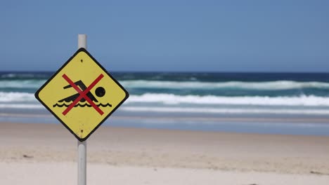 warning sign on beach, waves in background