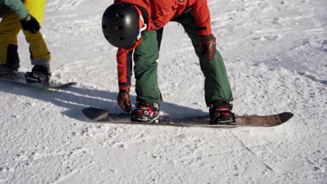 snowboarders fastening boots before going down the slope