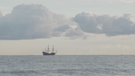 timelapse - 16th century galleon andalucia replica ship anchored in the distance in the mediterranean sea in a cloudy day at sunrise