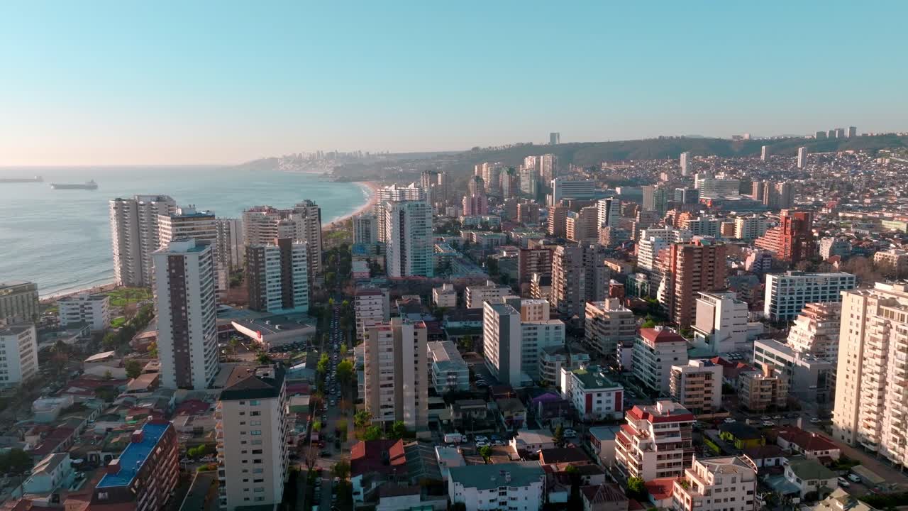 Dolly in aereo di edifici moderni del quartiere di Viña del Mar vicino alla costa del mare turchese all'ora d'oro, Cile
