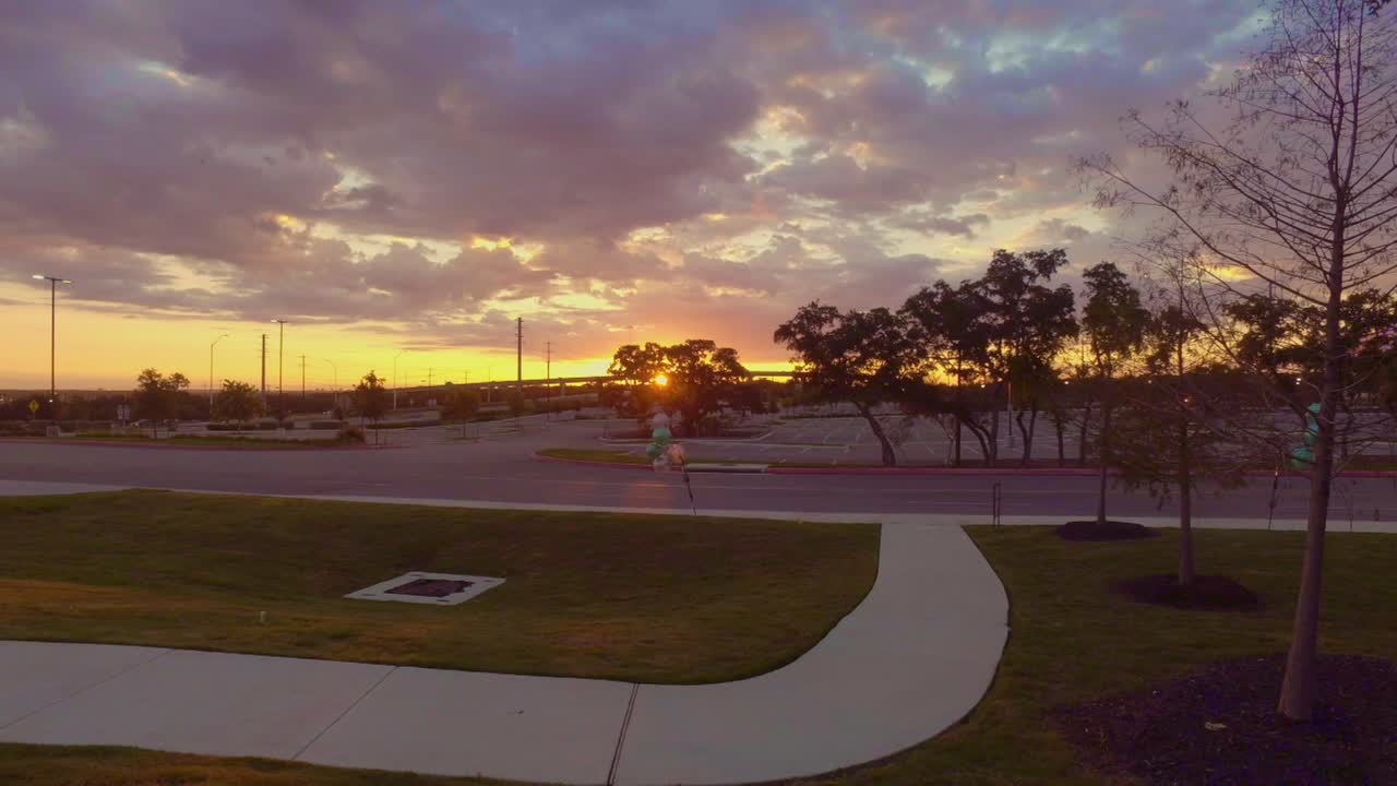 vueltas de tiempo de los autos que salen de los apartamentos para ir a trabajar temprano en la mañana con el amanecer en el fondo y el estacionamiento vacío por delante