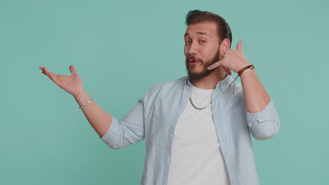 Lebanese-man-looking-at-camera-doing-phone-gesture-like-says-hey-you-call-me-back-conversation