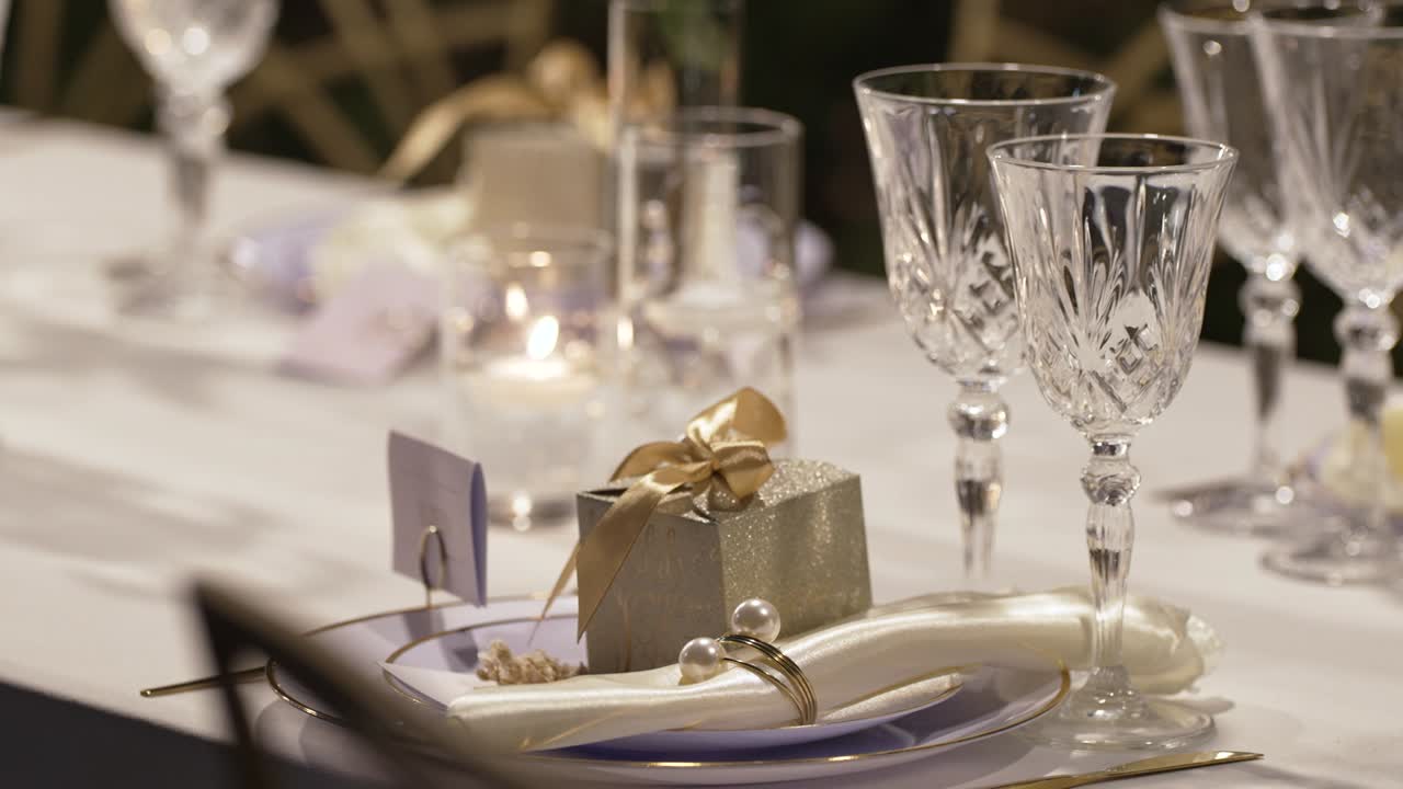 Et smukt bord er dækket til en særlig begivenhed med elegant service, funklende glas og smukt indpakkede gaver udendørs.