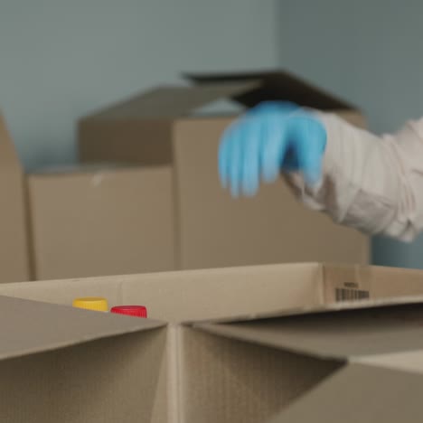 las manos de los voluntarios con guantes protectores ponen comida en una caja de envío