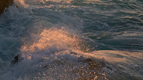 stormy ocean crashing on sunlight rocks outdoors close up. foaming sea breaking