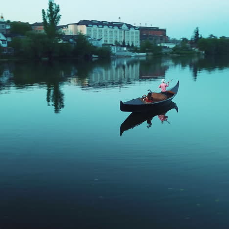 romantic view of a beautiful woman in a boat and a man in hat rowing on the evening. calm blue water of a river and gondola with a female relaxing at a summer night.