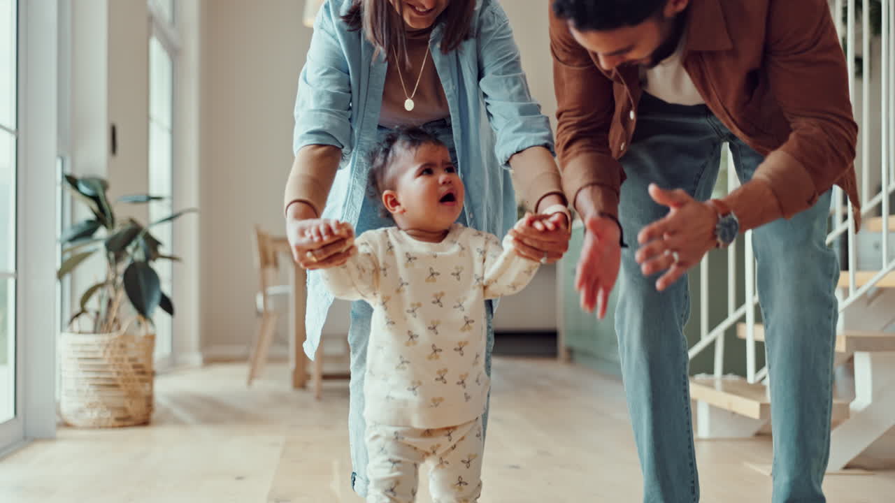 Parents helping their baby take first steps at home