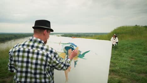 close-up of a painter wearing a hat and checkered shirt, focused on creating a masterpiece in a grassy field. in the background, a woman in a hat and white dress sits , posing for the painting