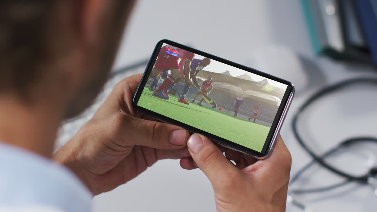 Medico uomo che guarda una partita di hockey sullo smartphone