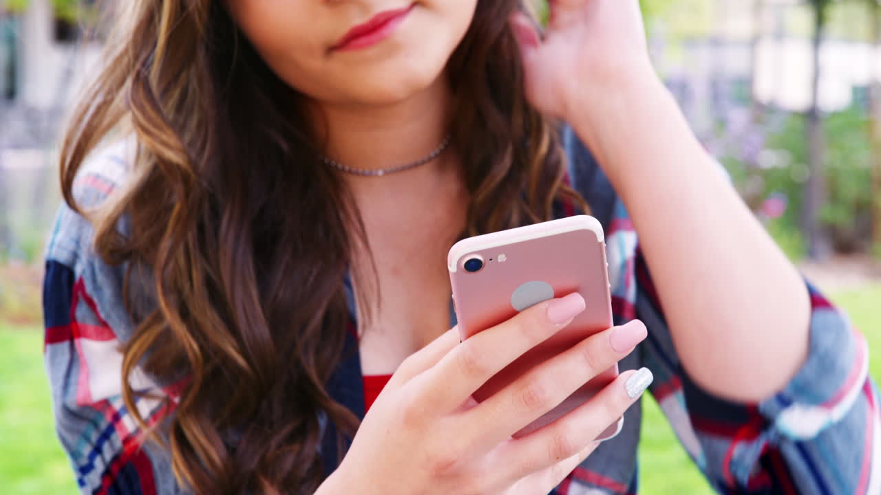 여자 고등학교 학생 이 대학 건물 밖 에서  ⁇ 드폰 으로 메시지 를 확인 하고 있다