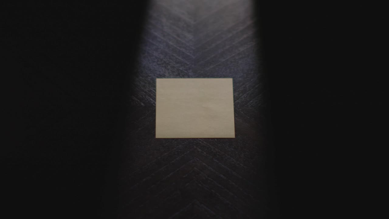 A weekday transition of a dramatic hand writing "Friday" in Sharpie on a Post it Note, picking up the note, and placing it back down. Shot in slow motion under sharp lighting
