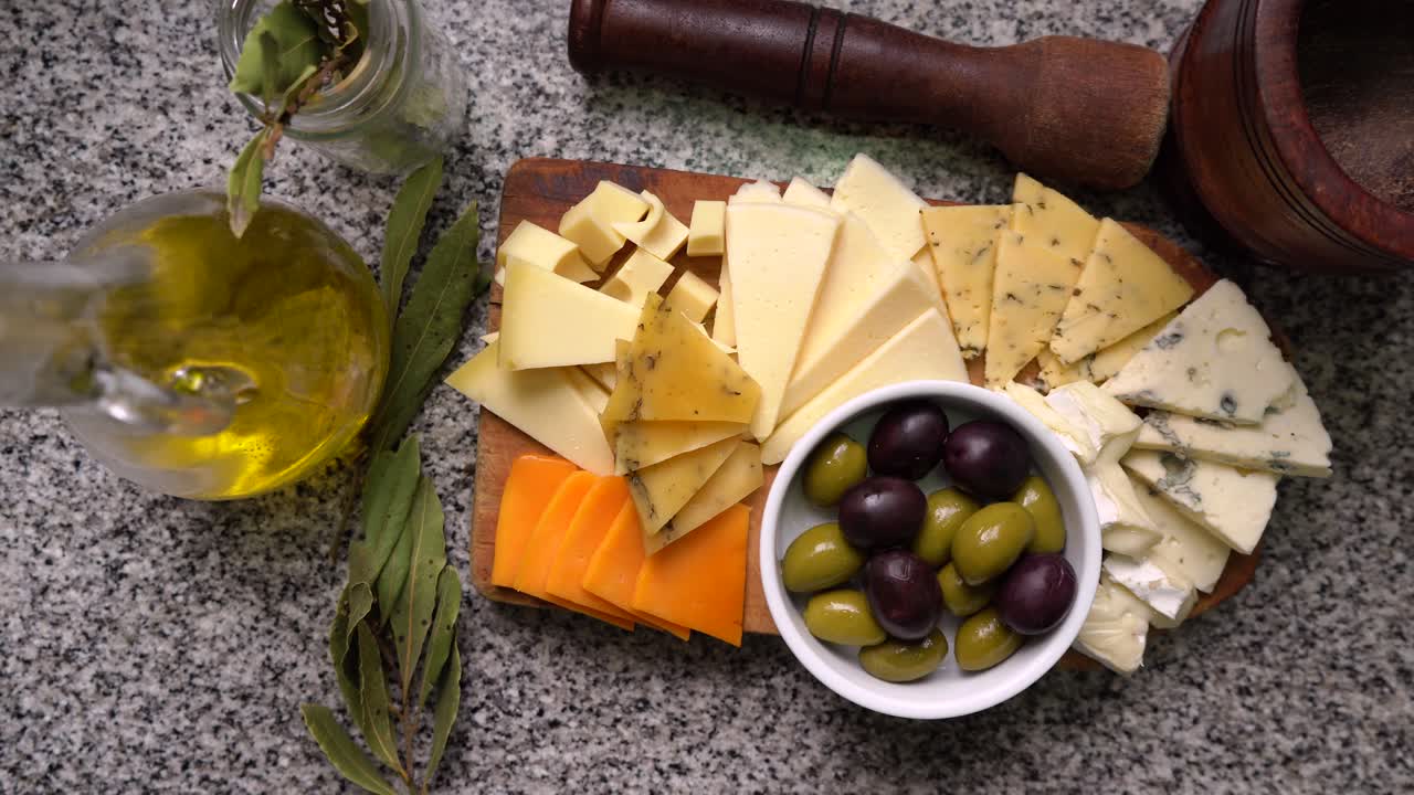Different types of cheeses accompanied by green and black olives