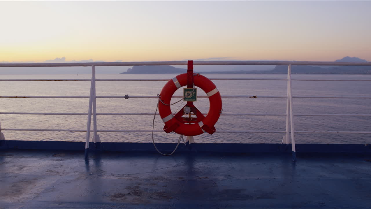 Red Lifebuoy on Ship Railing with Scenic Ocean View at Dawn