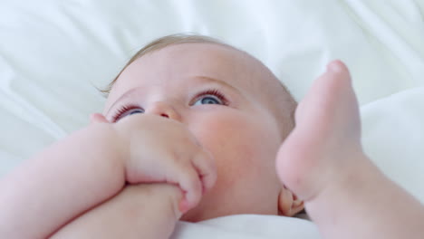 baby boy lying on bed and holding feet