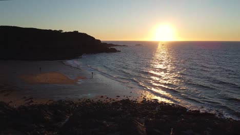 Toma-Aérea-De-Una-Hermosa-Puesta-De-Sol-Rodeada-De-Acantilados-En-La-Playa-De-Saussaye,-Cancale,-Francia-Y-El-Canal