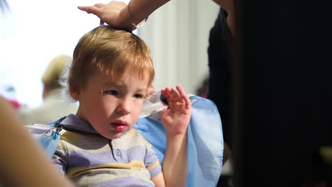 niño quitándose la capa durante el corte de pelo