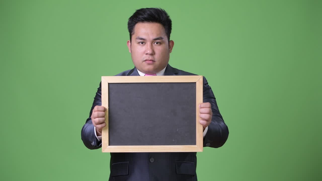 초록색 배경에 젊은 잘생긴 과체중 아시아 사업가