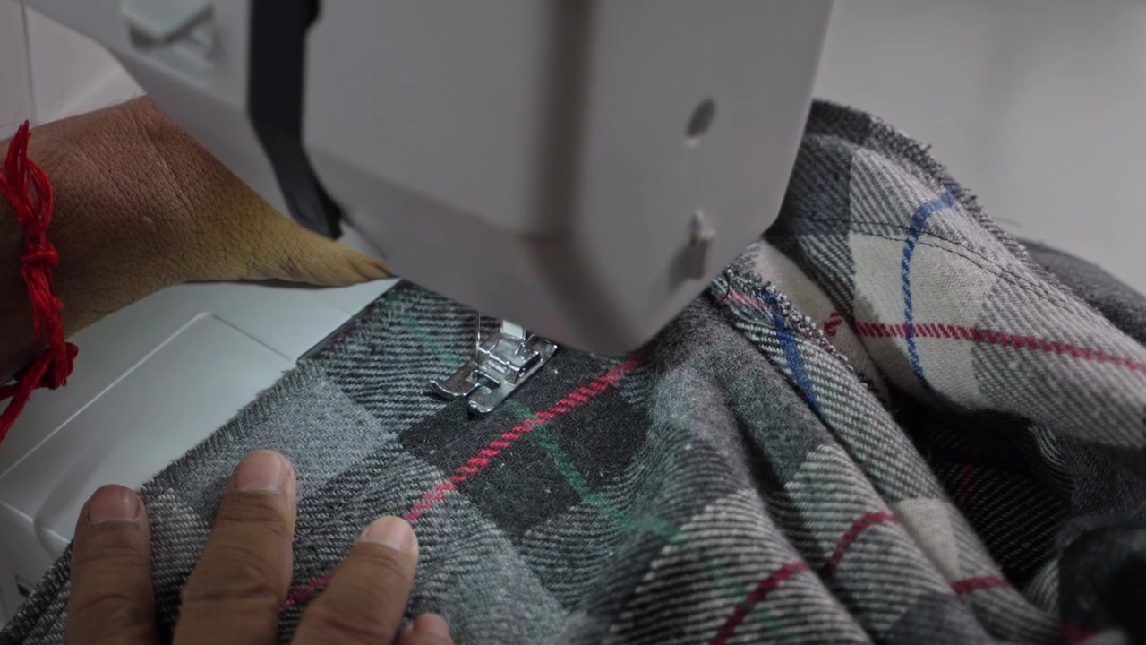 Man Stitching Clothes Using an Electric Sewing Machine