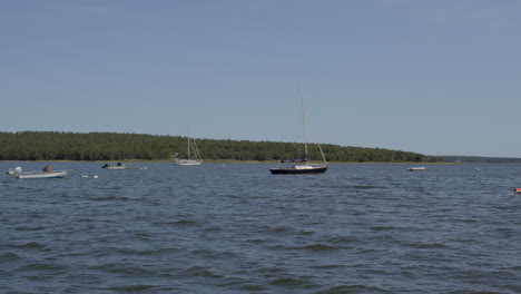 slow pan of boats floating in a lake in cape cod on a beautiful summer day