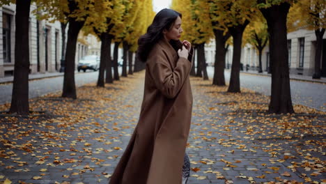woman walking on a cobblestone street lined with autumn trees