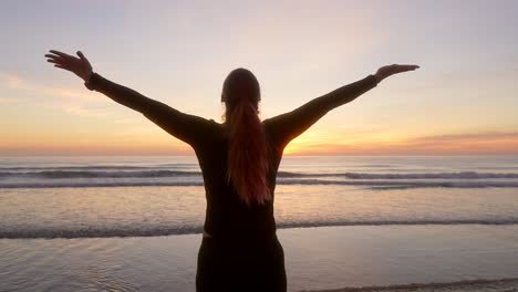 woman spreads her arms and watching the sunrise while breathing during sunrise