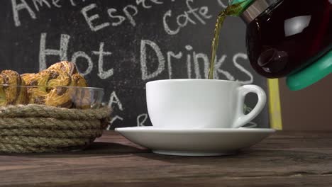 a cup of tea and homemade cookies on a cafe table.tea is pouring from a transparent teapot.menu.4k