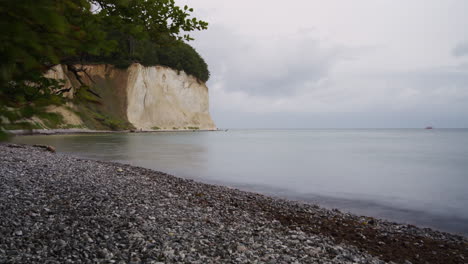 timelapse of clouds movement over white chalk cliffs on ruegen island, pebble beach and low tide