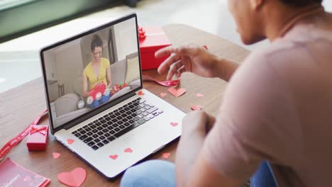 Fröhliche-Gemischtrassige-Frau,-Die-Ein-Geschenk-öffnet-Und-Einen-Videoanruf-Zum-Valentinstag-Auf-Dem-Laptop-Tätigt