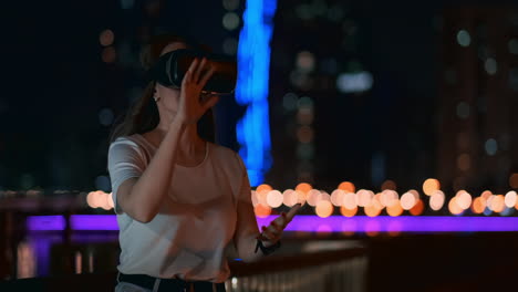 Ein-Junges-Mädchen-Mit-Einer-Virtual-Reality-Brille-In-Einer-Großen-Metropole-Simuliert-Die-Arbeit-In-Der-Virtual-Reality-Schnittstelle-Des-Programmspiels.-Das-Konzept-Der-Erweiterten-Realität