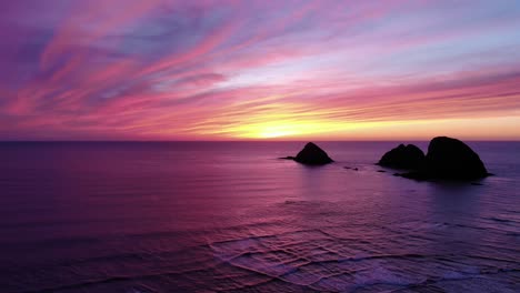 drone flies over ocean towards sea stacks and beautiful sunset