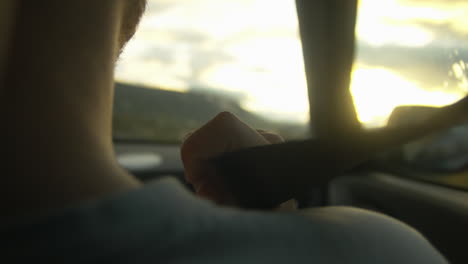 close up seat belt on shoulder of man driving at sunset in nature