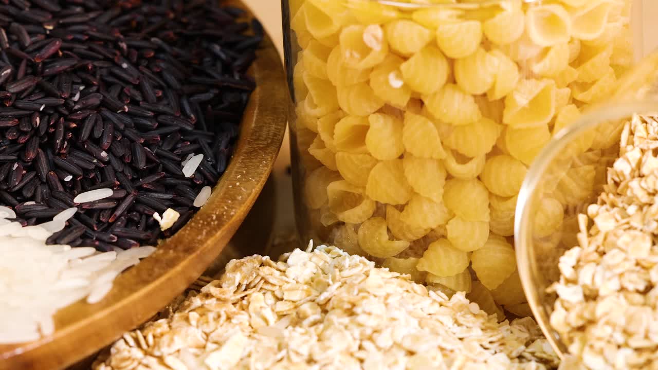 Close-up of various grains and pasta in glass jars, showcasing textures and colors under warm lighting