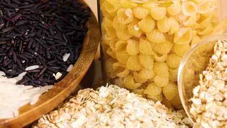 close-up of various grains and pasta in glass jars, showcasing textures and colors under warm lighting