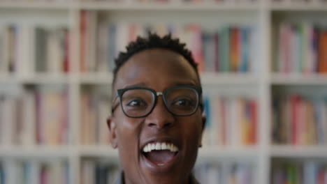 Porträt-Eines-Erfolgreichen-Jungen-Afroamerikanischen-Studenten,-Der-Lacht-Und-Den-Lifestyle-Erfolg-Genießt.-Intelligenter-Schwarzer-Mann,-Der-Aufgeregt-Aussieht-Und-Eine-Brille-Im-Bücherregal-Hintergrund-In-Zeitlupe-Trägt