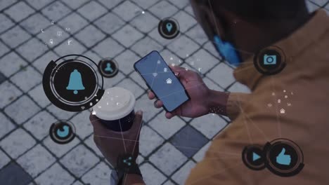 animation of media icons over african american man using smartphone