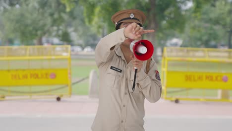 indian police officer controlling crows using megaphone