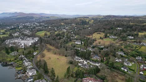 Vista-Aérea-Elevada-Del-Distrito-De-Los-Lagos-De-Windermere-Inglaterra-Reino-Unido-Con-Un-Velero-Con-Vela-Y-árboles-De-Color-Rojo-Marrón-En-Esta-Popular-Atracción-Turística