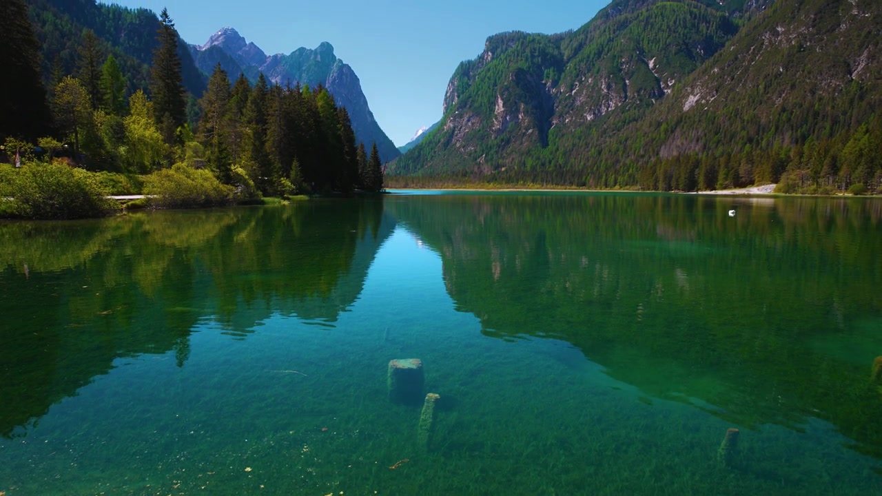 Acqua limpida del Lago di Dobbiaco che guarda a sud verso il Monte Cristallo nel Parco Naturale Tre Cime, Alto Adige, Italia.