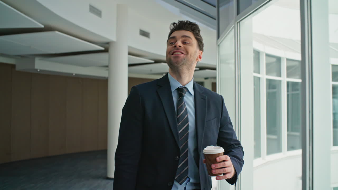 Confident ceo checking phone walking office hallway with coffee takeaway closeup