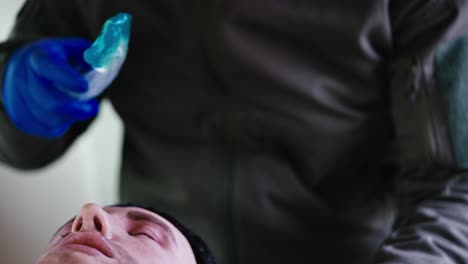 Close-up-shot-of-a-confident-man-in-a-military-doctor-in-blue-medical-gloves-applies-a-special-gel-to-place-a-breathing-tube-inside-the-mouth-of-a-male-doll-soldier-during-theoretical-and-practical-training-of-military-medics