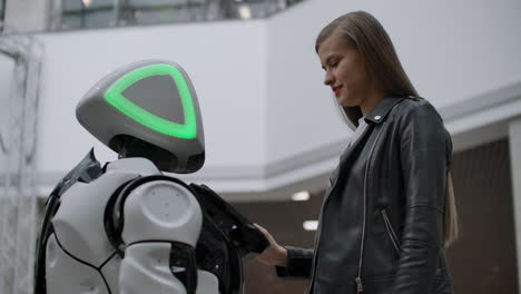 happy woman in contact with cyborg robot. click on the robot screen. a droid interacts with a woman