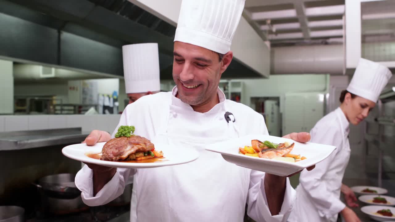 chef guapo sonriente mostrando dos platos a la cámara