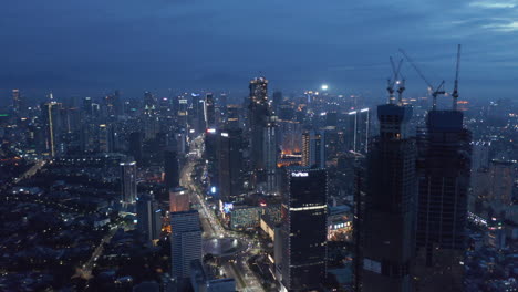 Aerial-truck-shot-of-night-time-cityscape-of-Jakarta-city-center-with-traffic-on-the-multi-lane-highway-around-Selamat-Datang-monument-roundabout