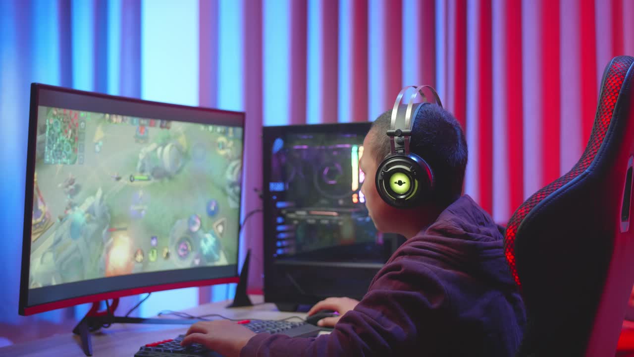 Young Boy Wearing Headphones Playing Video Game, Using The Keyboard Playing Video Game