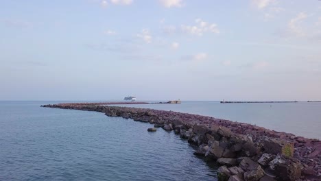 Aerial-view-of-large-white-cruise-liner-Seven-Seas-Splendor-arriving-at-the-port-of-Liepaja-,-early-morning-golden-hour,-water-transportation,-Baltic-sea,-vacation,-wide-shot-moving-forward