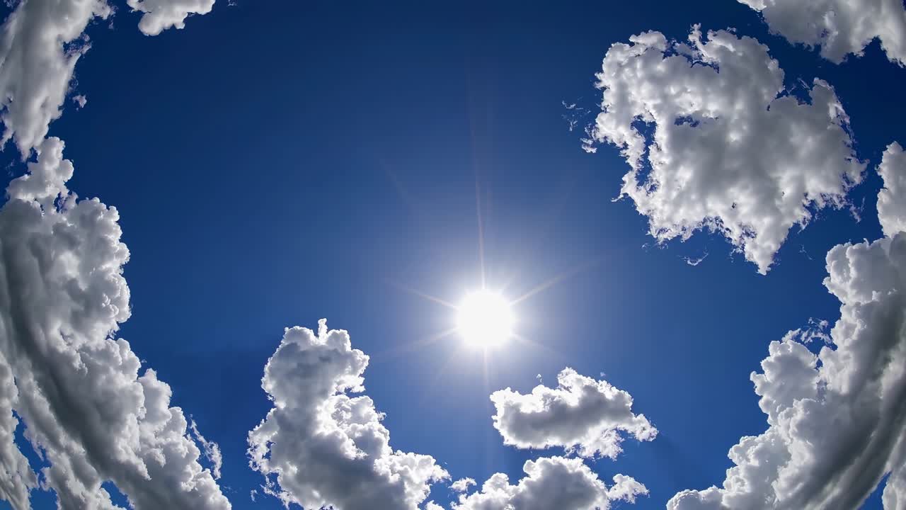 A serene video capturing fluffy clouds drifting across a vibrant blue sky, with the sun shining