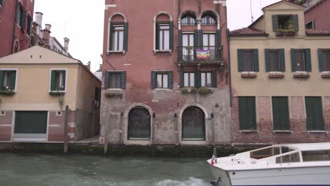 typical venetian architecture palace and buildings with canal as foreground with boat passing by on a cloudy spring day