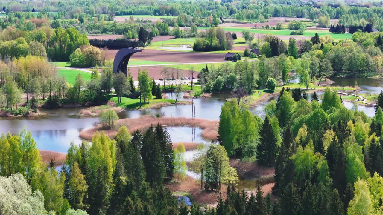 The Moon-shaped Kirkilai Observation Tower Provides Impressive Views of the Karst Lakes, Meandering Bridges, and Dense Foliage in Biržai Regional Park, Lithuania - Aerial Drone Shot