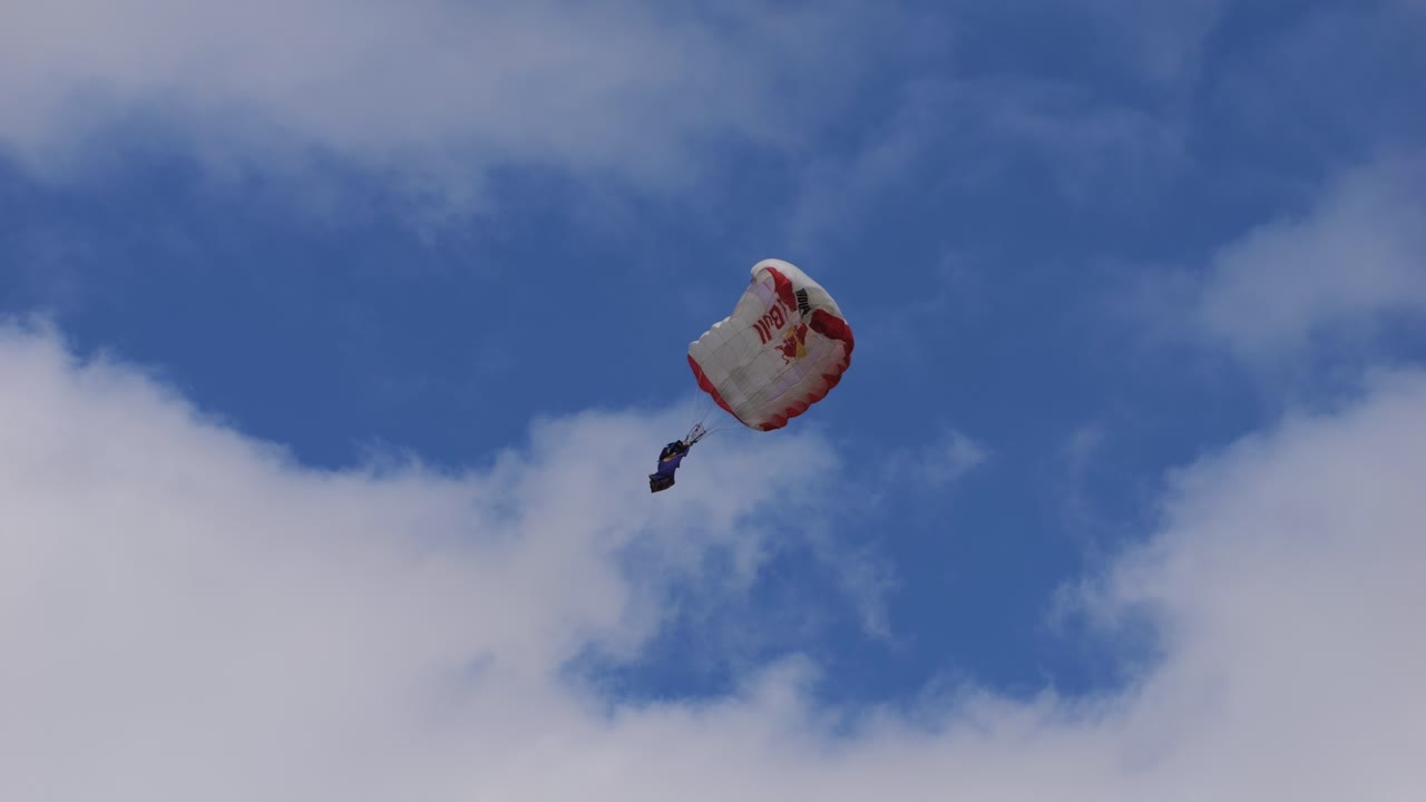Red Bull skydiver opens his chute and glides through the air before landing. Airpower 2024, slow motion