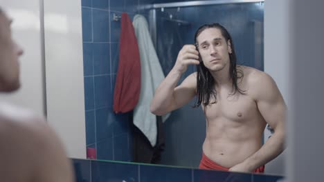 man combing his wet hair in the bathroom